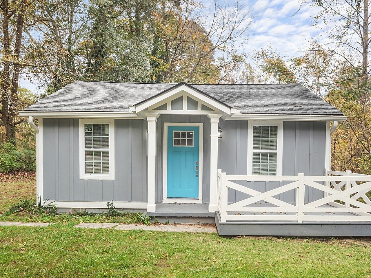 Cottage after renovation — new siding, porch rail, front door, landscaping