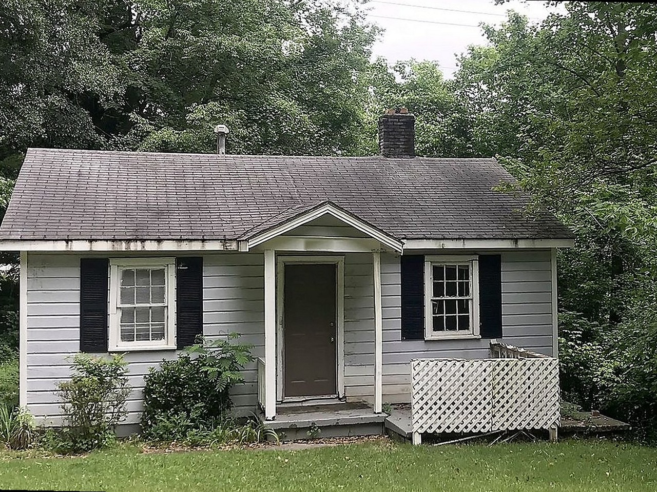 Cottage before renovation — overgrown, worn exterior