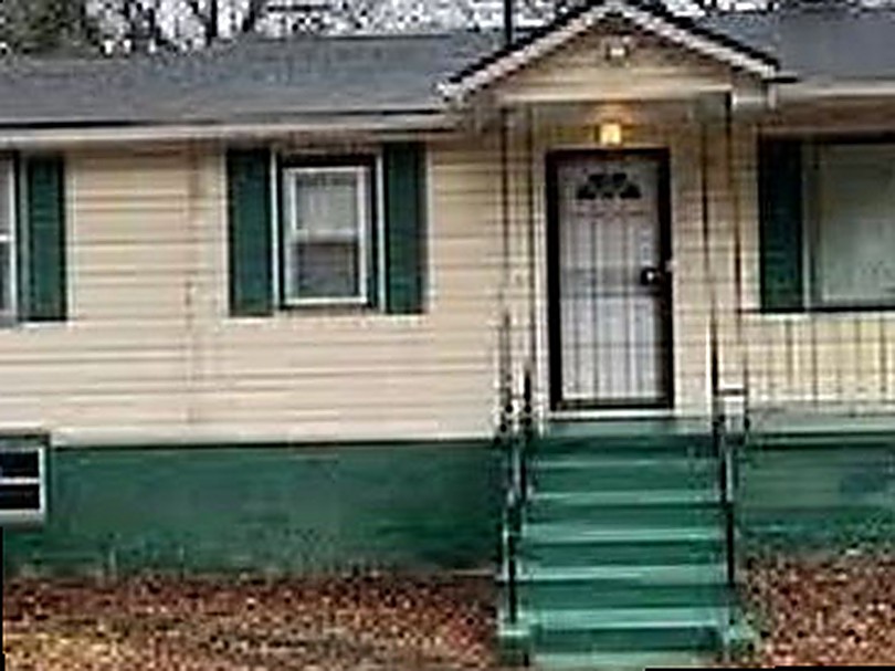 Small ranch before renovation — worn siding, green painted steps and trim