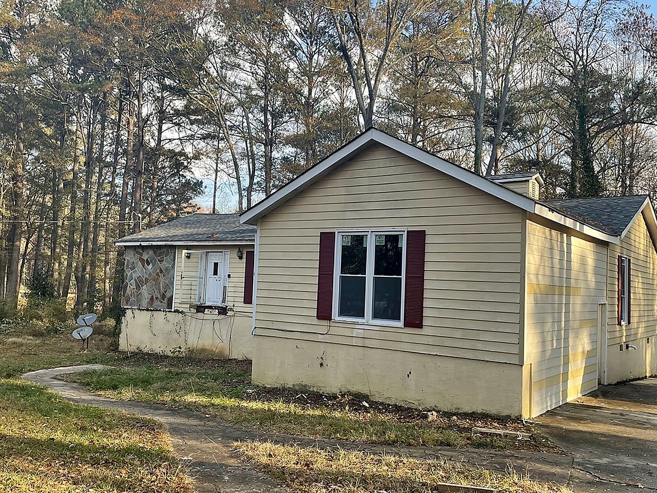 Cottage before renovation — faded siding, worn shutters, bare lot